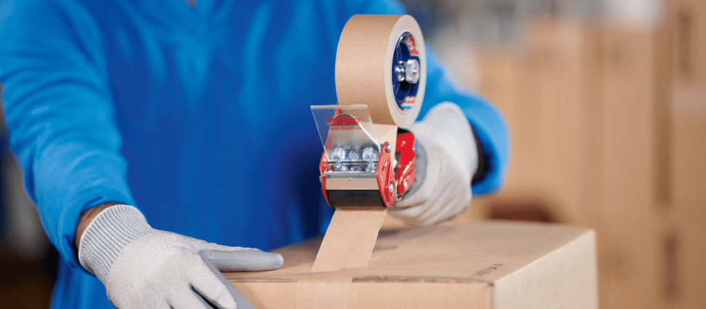Placing tape on a corrugate box using a tape gun.