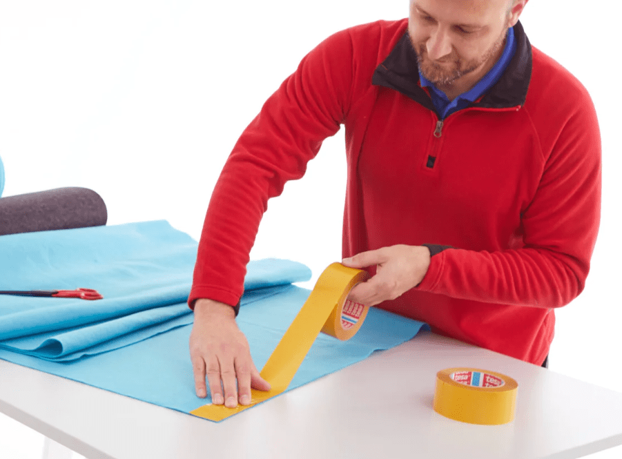 Applying adhesive transfer tape to a cloth.