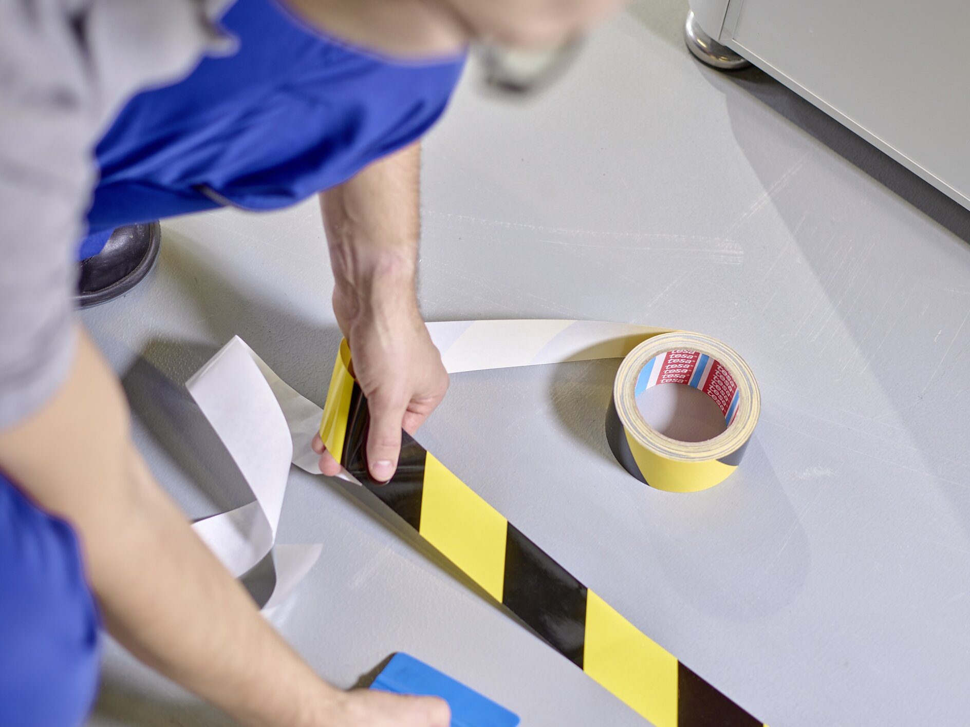 Applying caution floor marking tape in a warehouse