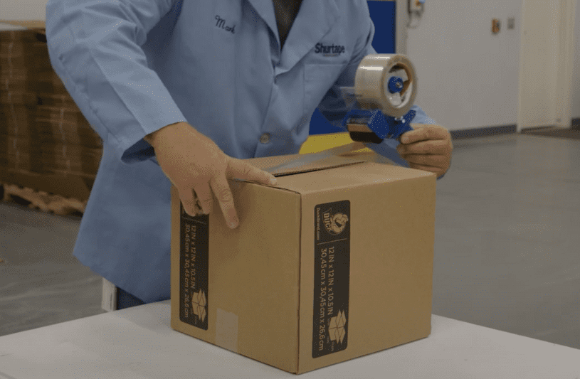 Hot melt tape being applied to a corrugate box using a tape dispenser