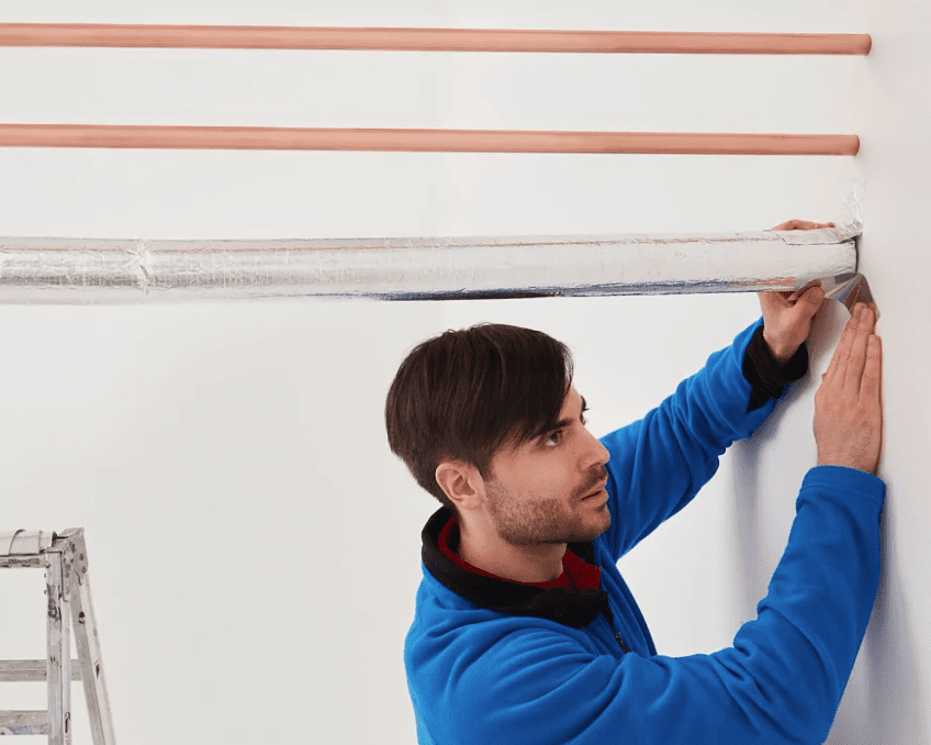 Applying reflective tape to pipes.